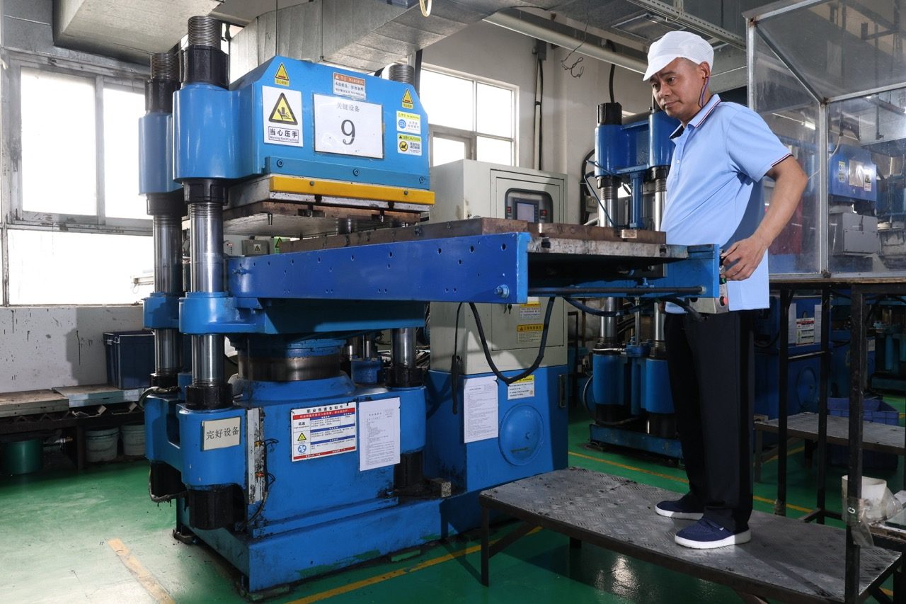 Operator standing beside blue hydraulic molding press