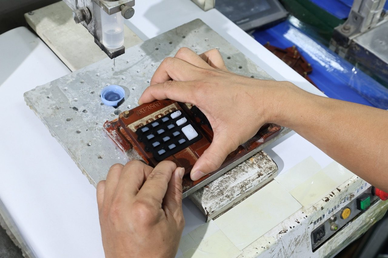 Worker positioning composite keypad assembly in mold fixture