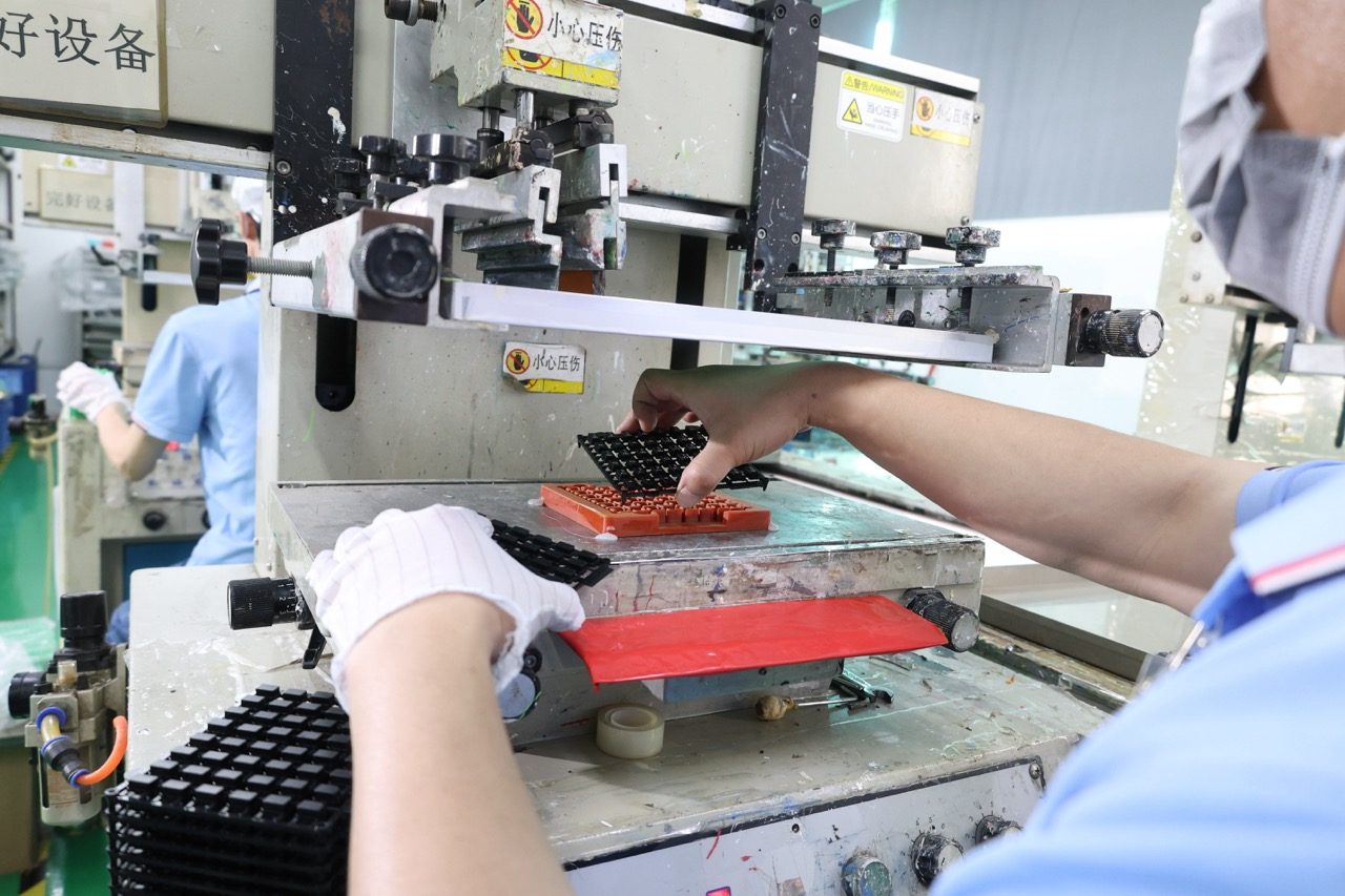 Operator placing black keypad sheet into transfer press